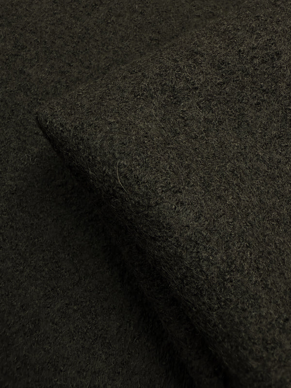 A close-up of Super Cheap Fabrics' Boiled Wool - Forest Night (152cm), featuring a dark brown, textured surface and folded edge—perfect for extra heavy weight winter garments.