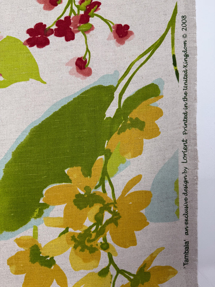 Pure Linen - Garden Reverie - 150cm by Super Cheap Fabrics features a floral yellow, green, and red pattern on cream. Text on the selvage reads: “Tambal, an exclusive design by Conker. Printed in the United Kingdom © 2008.”.