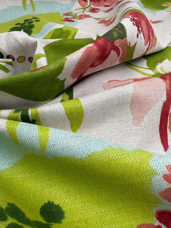 Close-up of Super Cheap Fabrics' Pure Linen - Garden Reverie - 150cm, showing a floral pattern in green, pink, red, and blue on a light background with visible woven texture.