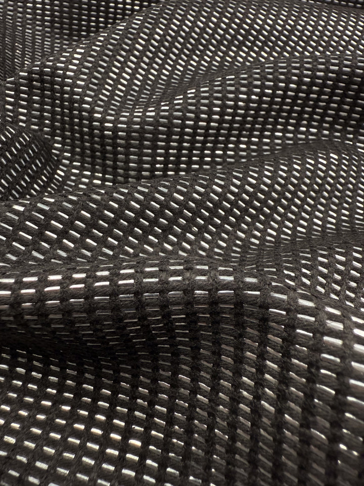 Close-up of Super Cheap Fabrics’ Linen Blend - Silver Dash (135cm): a luxury fabric featuring a grid of small white dashes on black, creating a textured, wavy surface ideal for upholstery.