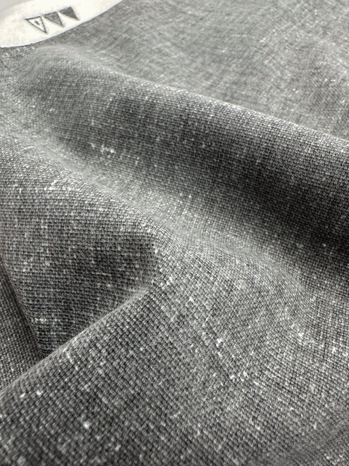 Close-up of Super Cheap Fabrics' Upholstery Canvas - Silver - 140cm, a heavyweight cotton with fine weave and soft, mottled texture. The gently folded fabric creates shadows and highlights, ideal for a cozy yet elegant upholstery finish.