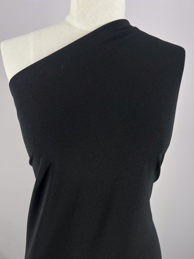 A mannequin displays a chic, medium-weight black dress made from Crepe Lycra, measuring 148cm, by Super Cheap Fabrics against a plain gray backdrop.