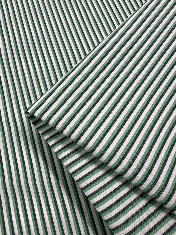 Shirting - Lizard - 150cm by Super Cheap Fabrics features lightweight green and white striped polyester cotton with overlapping diagonal and horizontal folds, ideal for versatile multicolour design projects.