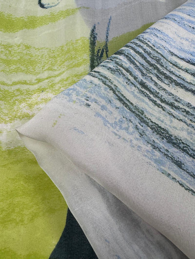 Close-up of Pure Silk - Speed from Super Cheap Fabrics, featuring luxurious abstract patterns: wavy blue and green lines on light background and softer green shades. The textures offer a layered, flowing look ideal for high-end fashion designs. Width: 112cm.